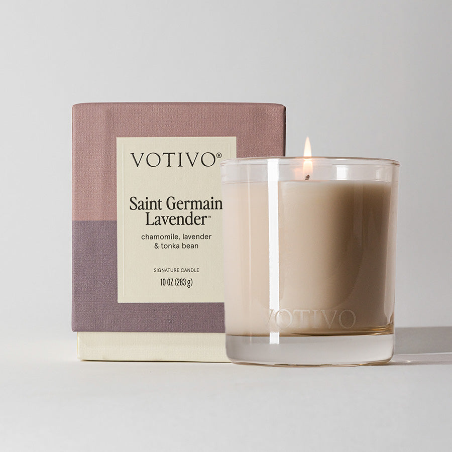 A Votivo Saint Germain Lavender 10 oz. Signature Candle in a clear glass holder is shown with its box—this premium soy blend candle features soothing lavender, chamomile, and tonka bean notes.