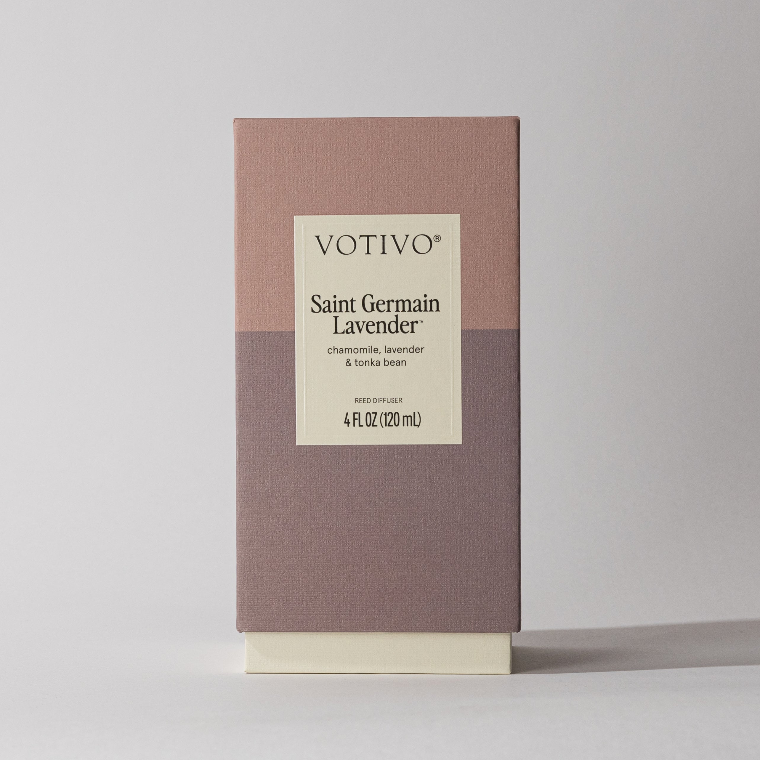 The Votivo Saint Germain Lavender Reed Diffuser comes in a rectangular box with a mauve and taupe design and a centered label listing chamomile, lavender, and tonka bean. This Signature Reed Diffuser delivers an elegant floral scent.