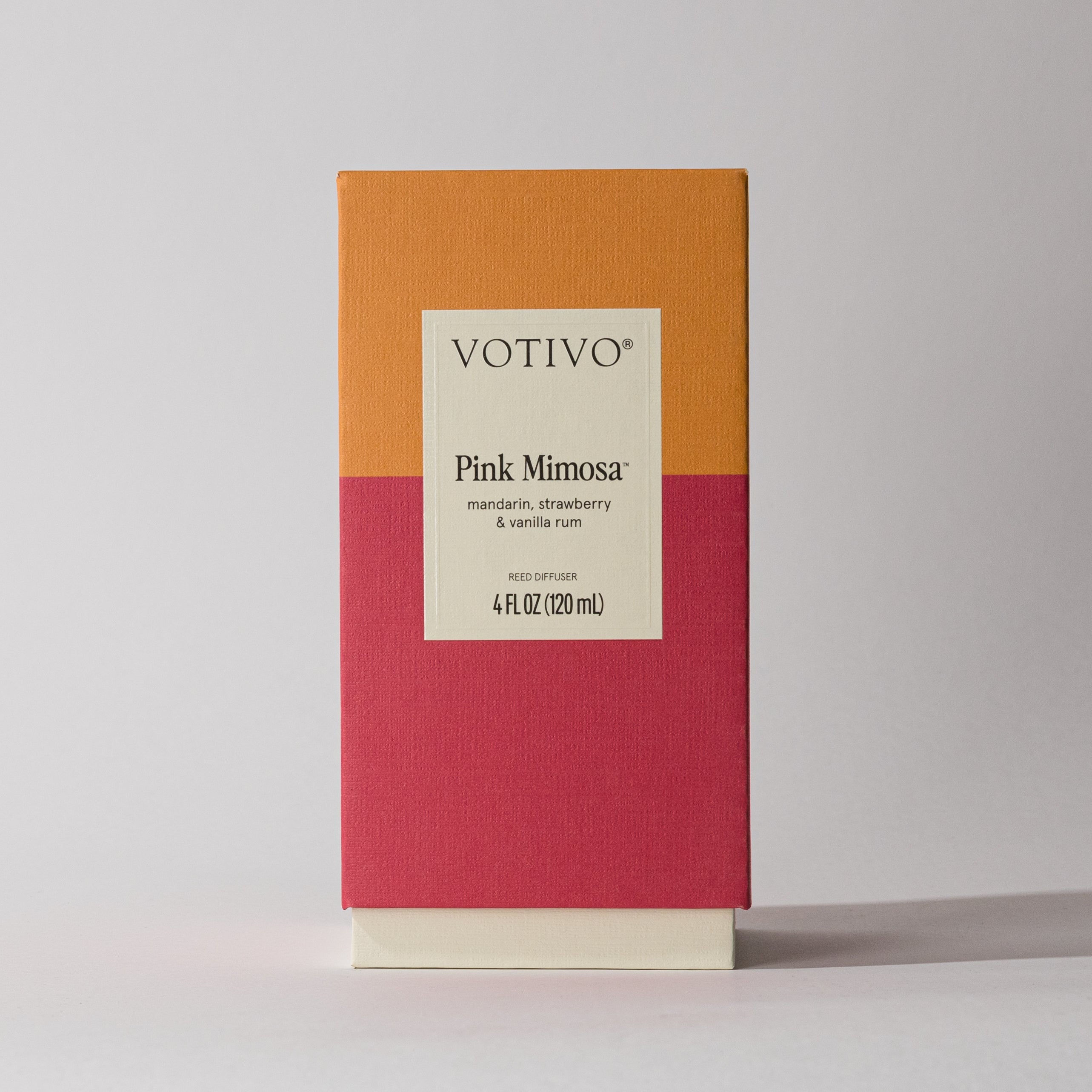 The Votivo Pink Mimosa Reed Diffuser comes in a rectangular box with orange and pink color blocks, offering a fruity mandarin, strawberry, and vanilla rum fragrance in a 4 fl oz (120 ml) size.