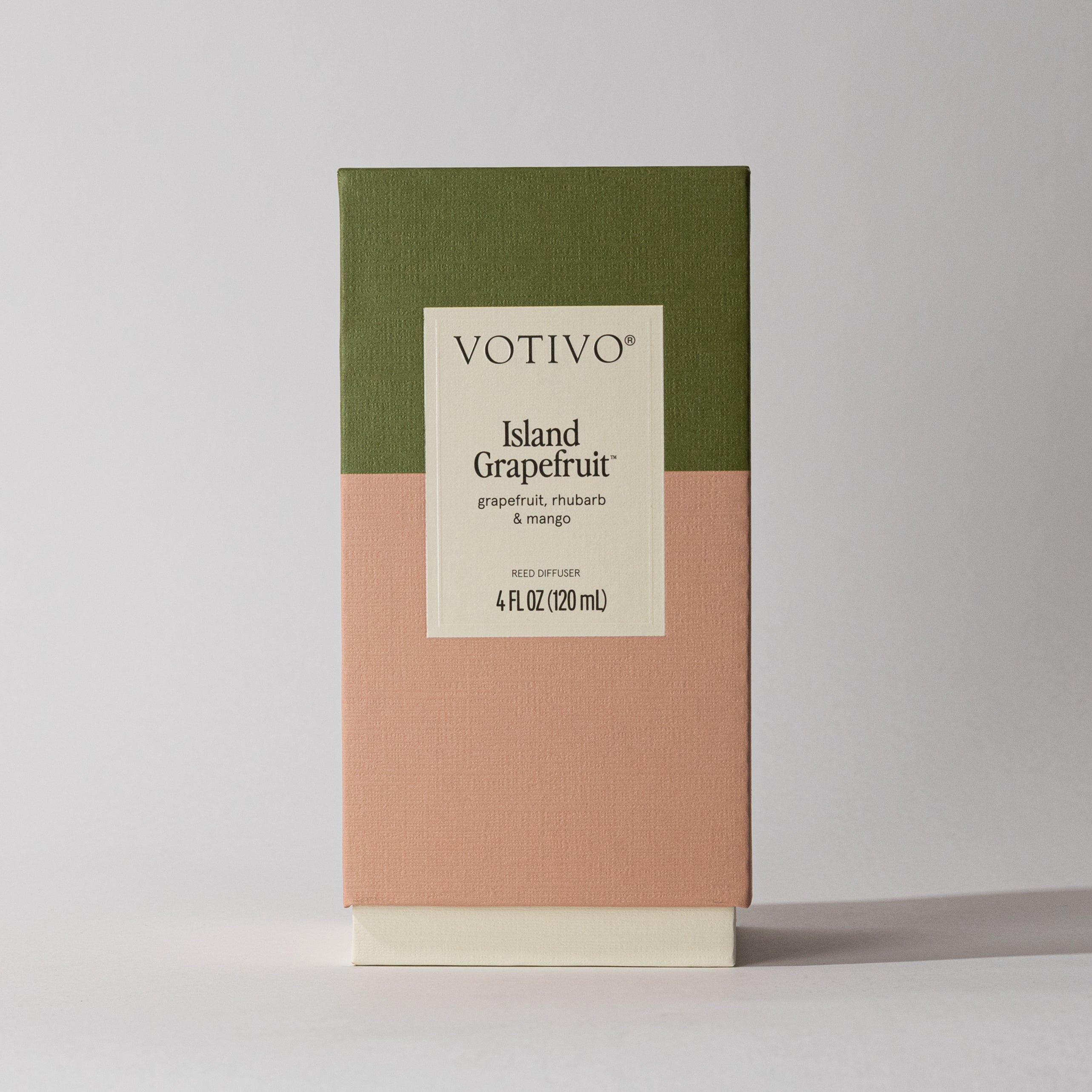A Votivo Island Grapefruit Reed Diffuser (4 fl oz/120 ml) with a green and peach color block box and cream label, featuring citrus notes of grapefruit, rhubarb, and mango, stands on a light surface.