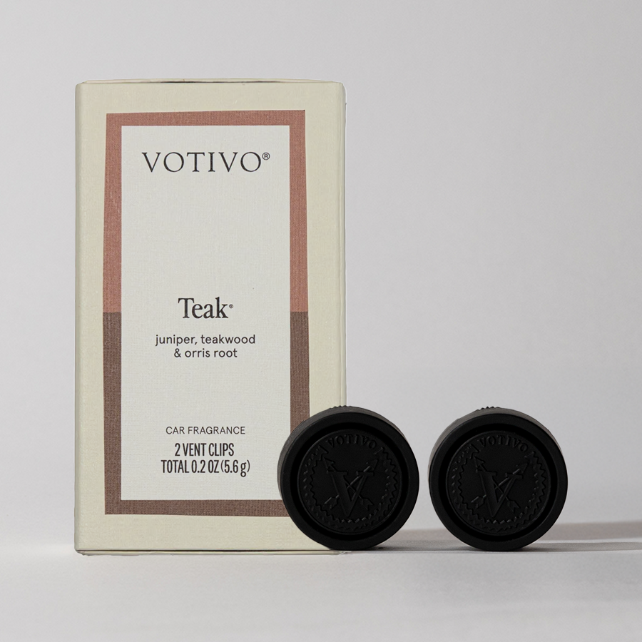 A box of Votivo Teak Car Fragrance (2 Pack) with two black vent clips is displayed. The packaging notes a blend of teak, juniper, and orris root scents, set against a plain neutral background.