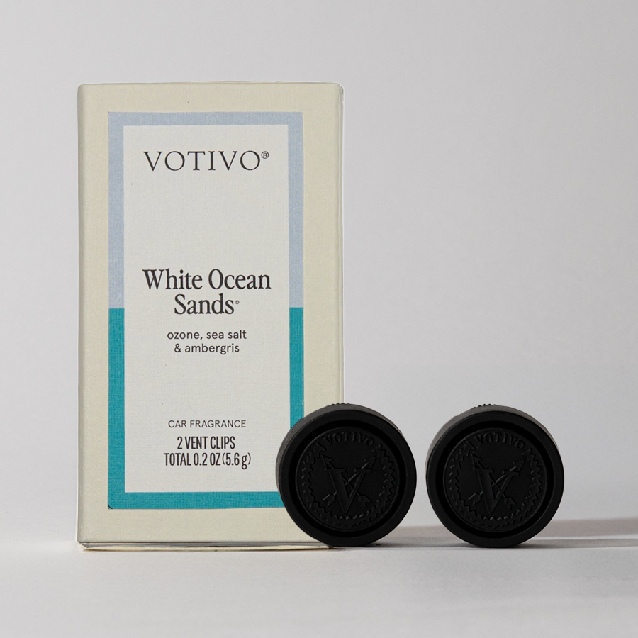A Votivo White Ocean Sands Car Fragrance (2 Pack) box with two black vent clips is shown. The packaging notes ozone, sea salt, and ambergris scents, and lists a total weight of 0.2 oz (5.6 g).