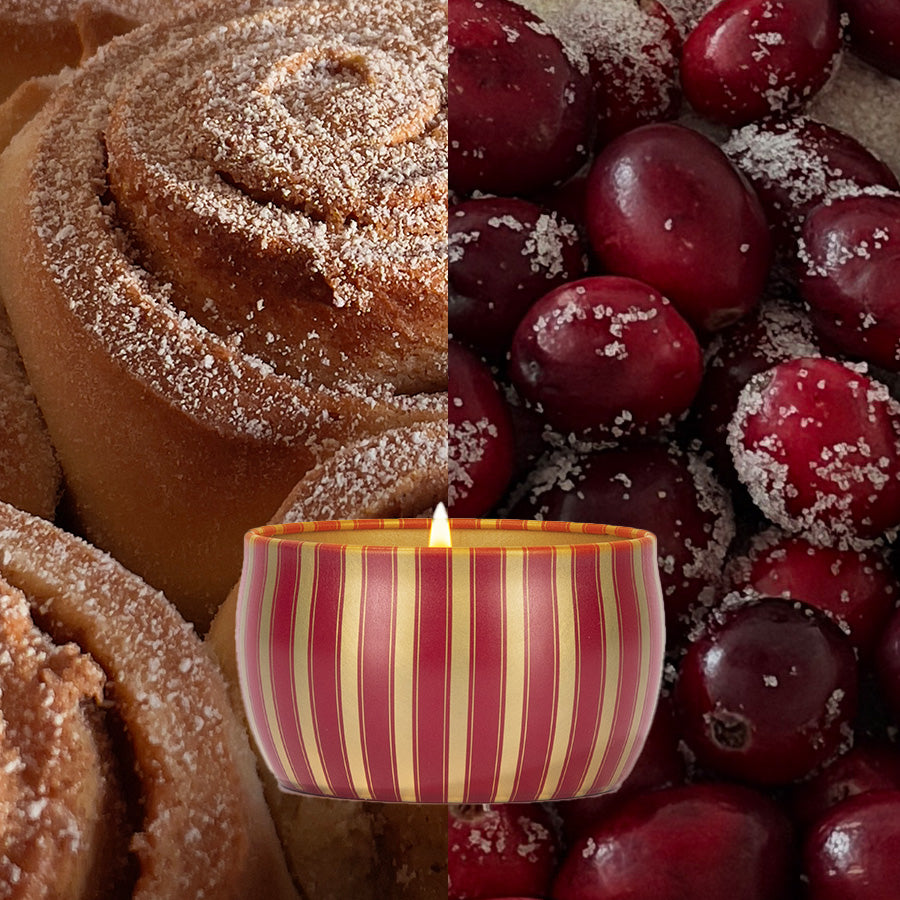 A Votivo Velvet Rouge Holiday Tin Candle with a glowing flame sits between close-up views of cinnamon rolls and sugared cranberries, showcasing its festive soy wax aroma.