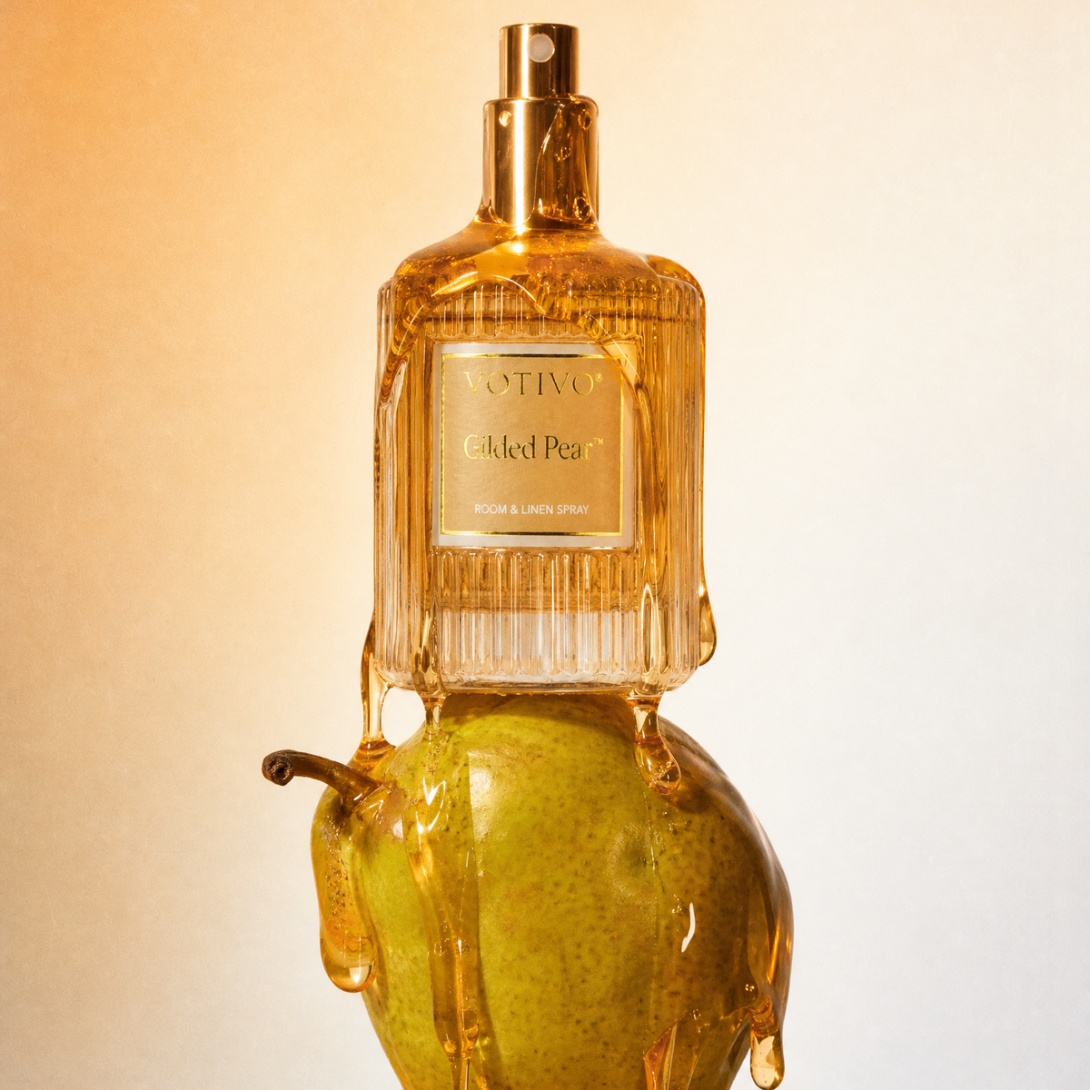 A Gilded Pear Room Spray dripping with honey sitting on top of a pear