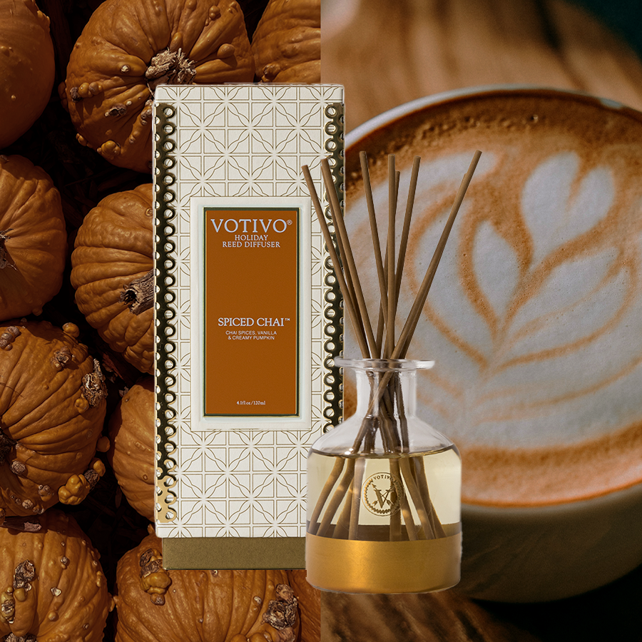 A Votivo Spiced Chai Holiday Reed Diffuser is displayed with small pumpkins and a latte, creating a cozy autumn vibe with warm, spicy notes.