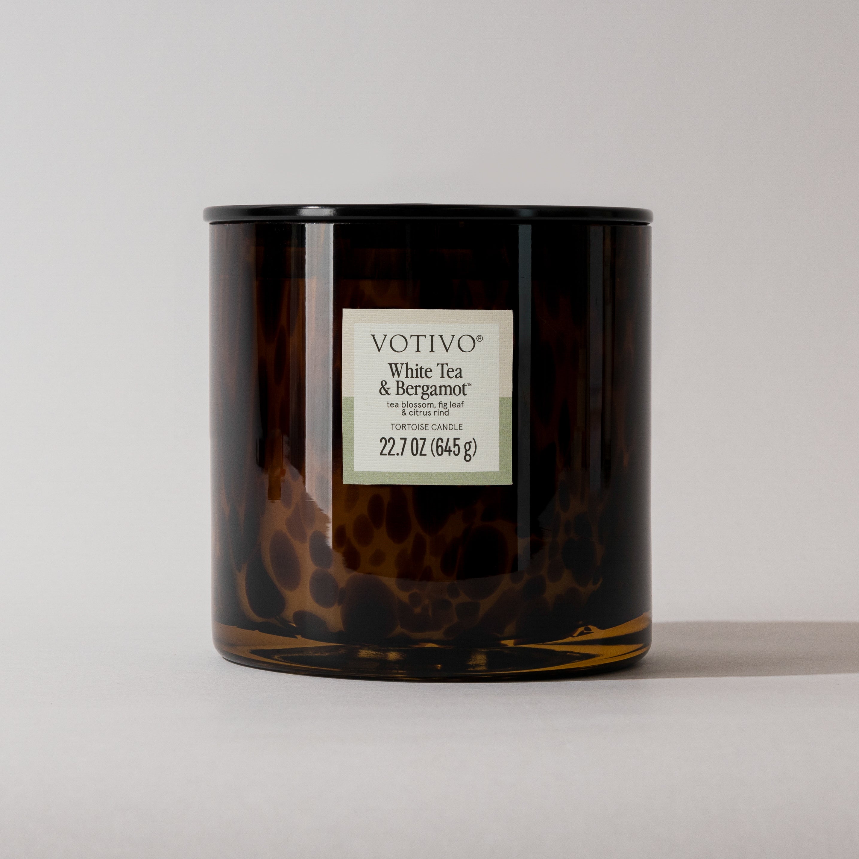 A brown glass tortoise candle jar labeled "Votivo White Tea & Bergamot Tortoise Candle" is shown against a plain, light background.
