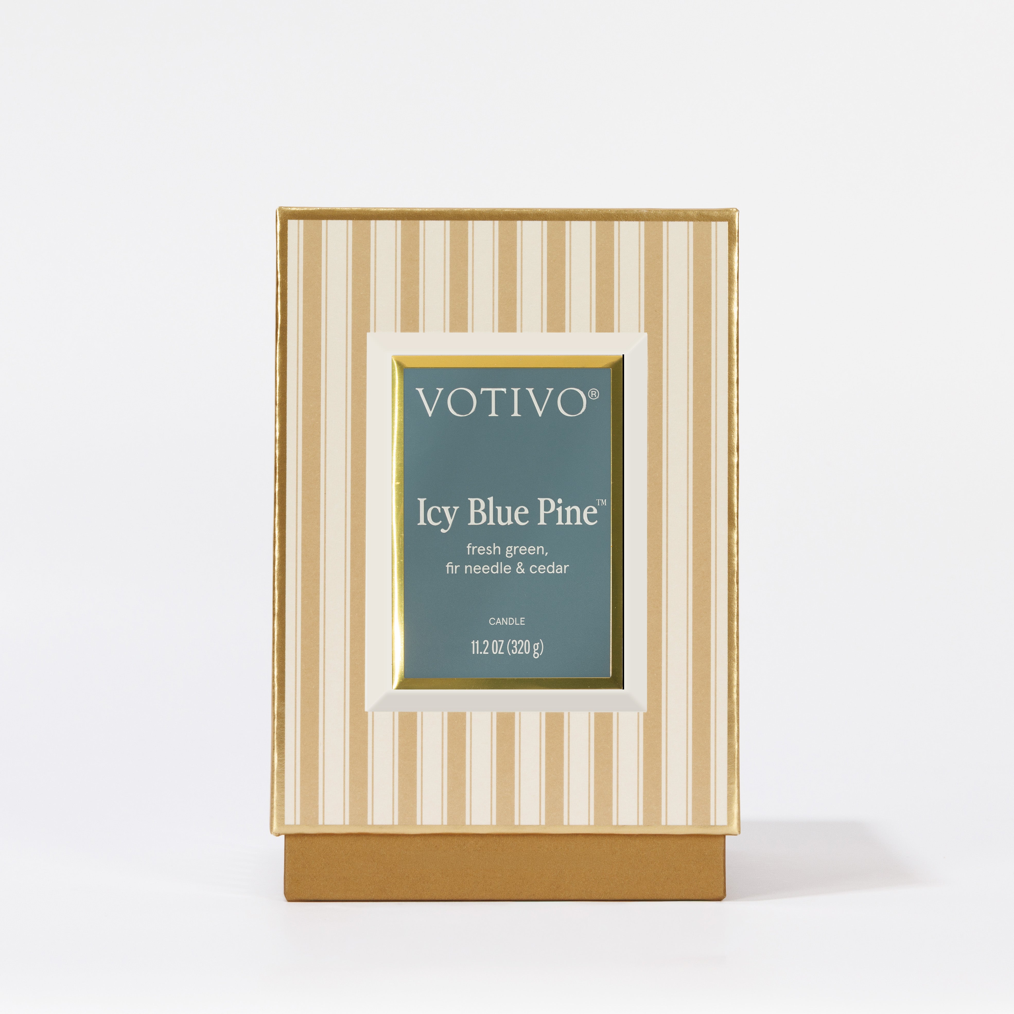 The Votivo Icy Blue Pine Holiday Candle features fresh green, fir needle, and cedar notes in a gold and cream striped box with a green label. This soy blend wax candle stands upright against a white background.