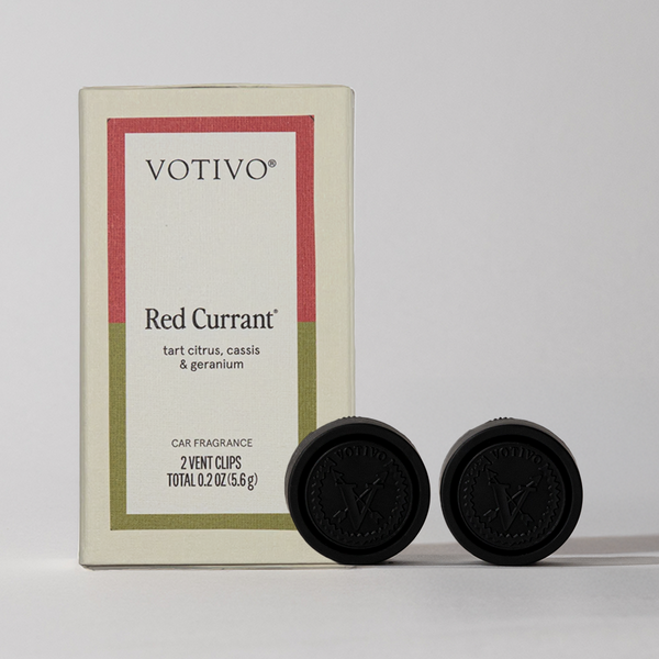 A Votivo Red Currant Car Fragrance (2 Pack) box, labeled with tart citrus, cassis & geranium notes, sits beside two black vent clips against a light background—enjoy the signature scent on every drive.