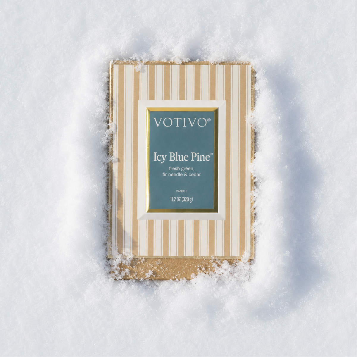 An Icy Blue Pine Boxed Candle sitting in fluffy, white snow