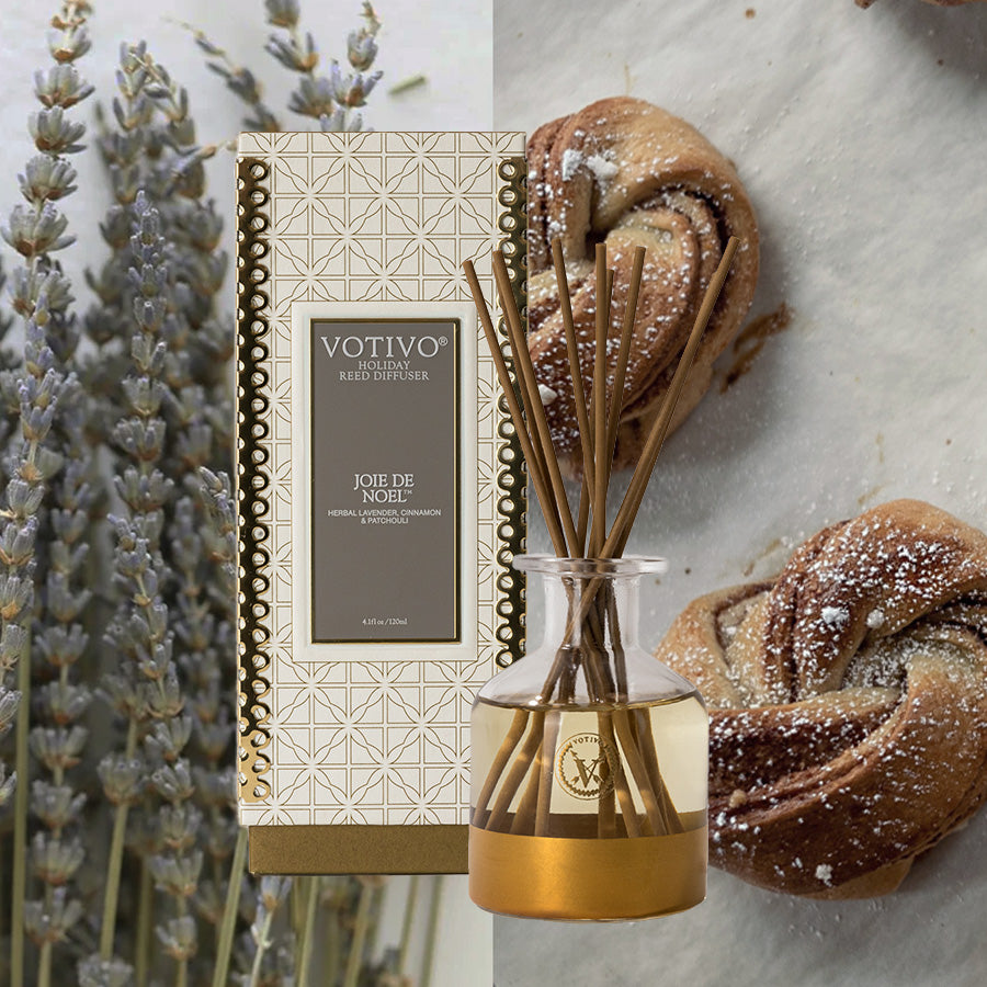 A Votivo Joie de Noel Holiday Reed Diffuser is displayed beside a clear jar of reeds, with lavender sprigs and powdered sugar pastries in the background, evoking an Oriental & Spice ambiance.