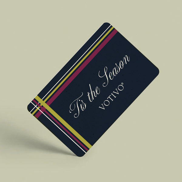 A Votivo E-Gift Card featuring ‘Tis the Season in elegant white script, highlighted by red, gold, and white diagonal stripes on a light beige background.