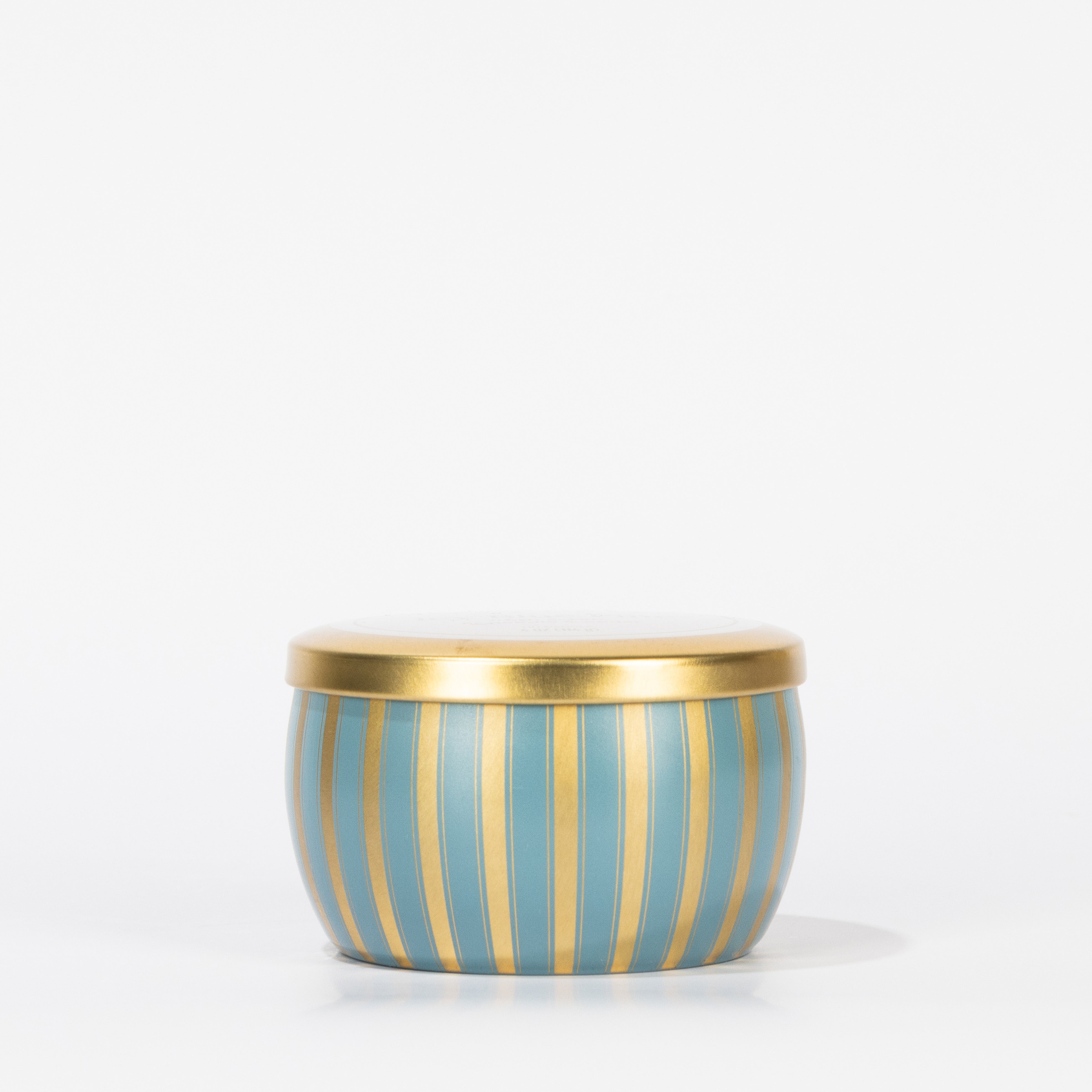 The Votivo Icy Blue Pine Holiday Tin Candle features a small round tin with a gold lid and icy blue and gold pine stripes, crafted from soy blend wax, displayed against a plain white background.