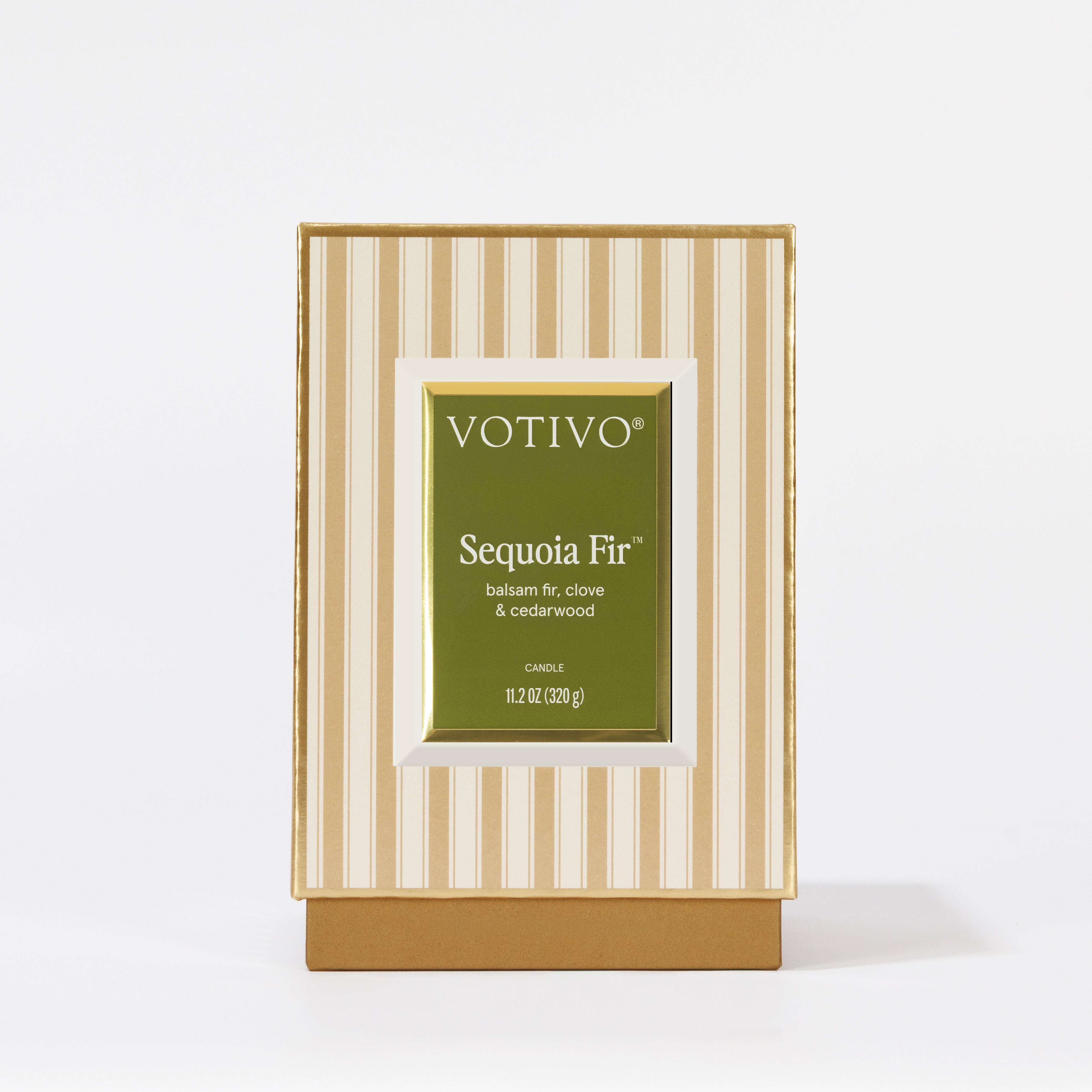 A Votivo Sequoia Fir Holiday Candle, crafted with premium soy blend wax, stands upright on a white surface in its box featuring a green label with white text and a striped beige and cream background.